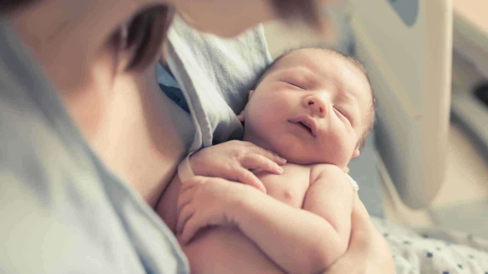 newborn baby sitting in mom's arms in the hospital after being born