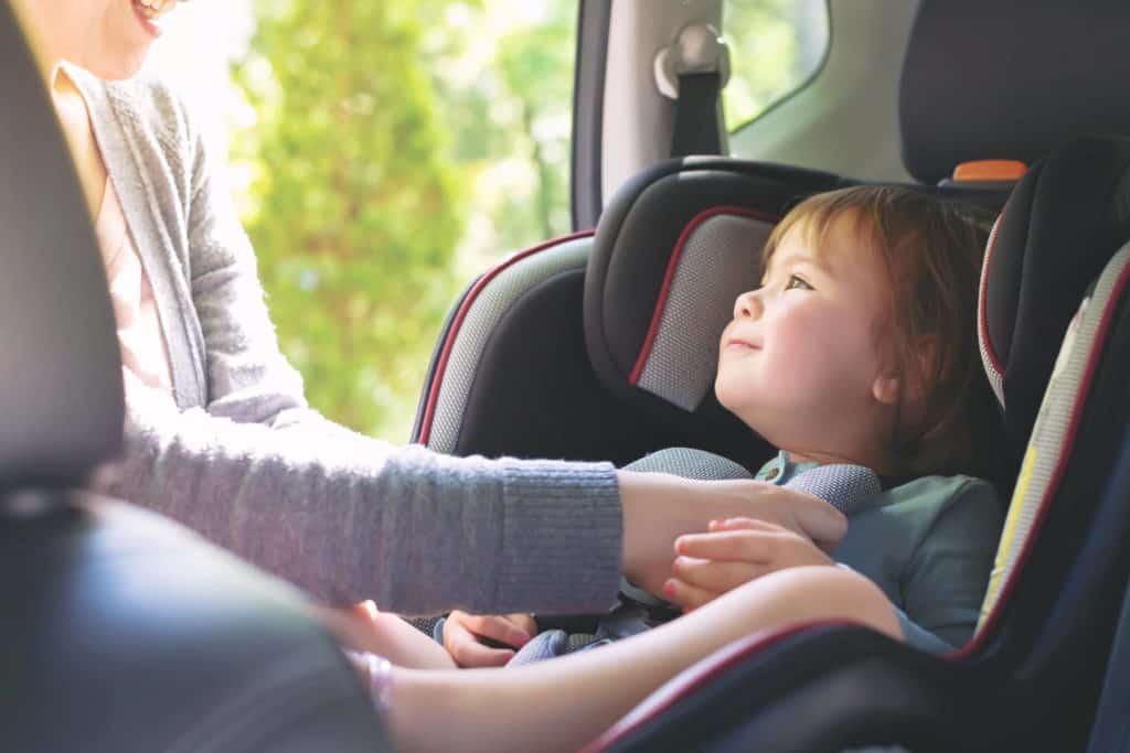 mom buckling toddler into non-toxic car seat