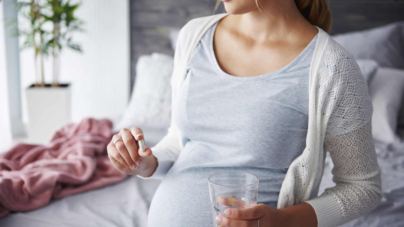pregnant woman holding probiotic capsule
