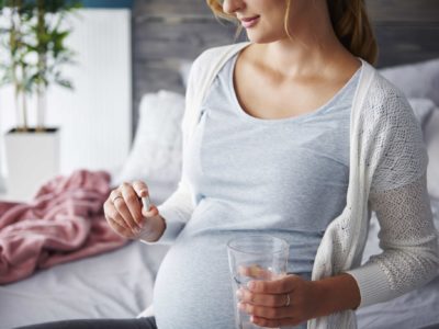 pregnant woman holding probiotic capsule