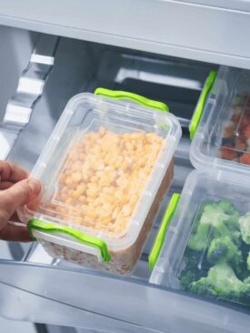 hand placing plastic storage containers with food in fridge