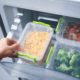 hand placing plastic storage containers with food in fridge