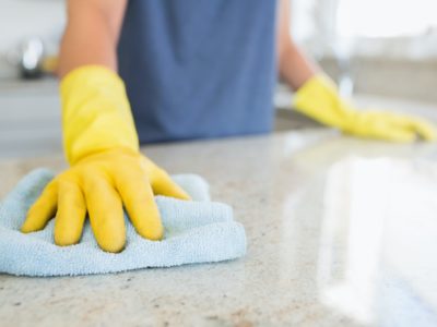 gloved hand wiping countertops with natural non-toxic cleaning products