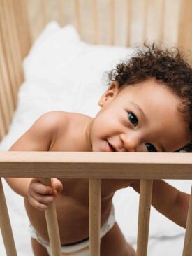 toddler standing in wooden crib