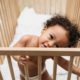 toddler standing in wooden crib