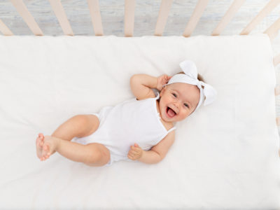 happy baby lying on certified organic crib mattress