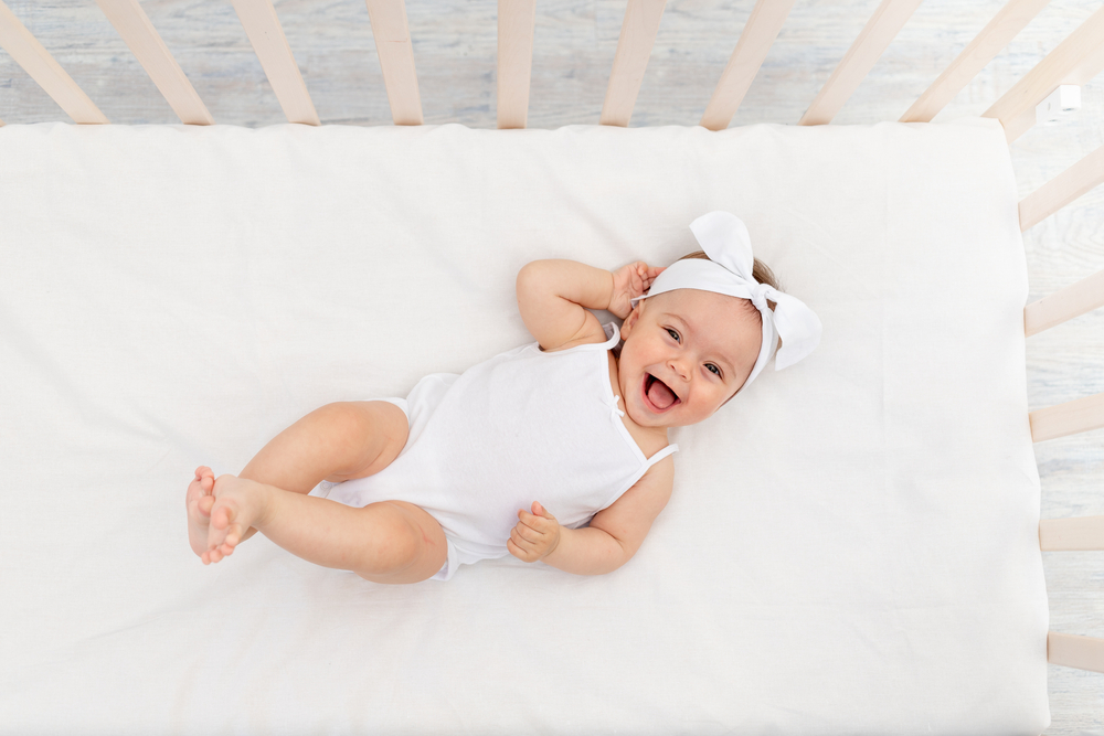 happy baby lying on certified organic crib mattress