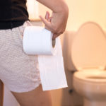 woman holding toilet paper in bathroom after using natural constipation treatment during pregnancy