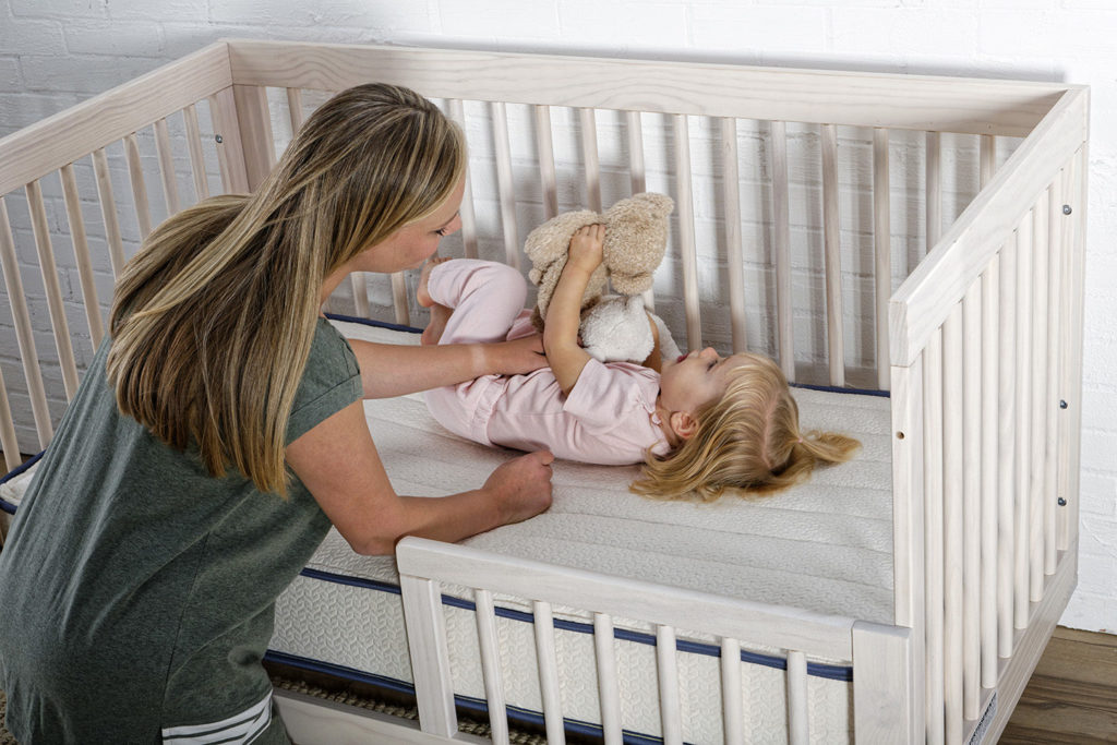 toddler lying in crib on emily mattress from my green mattress