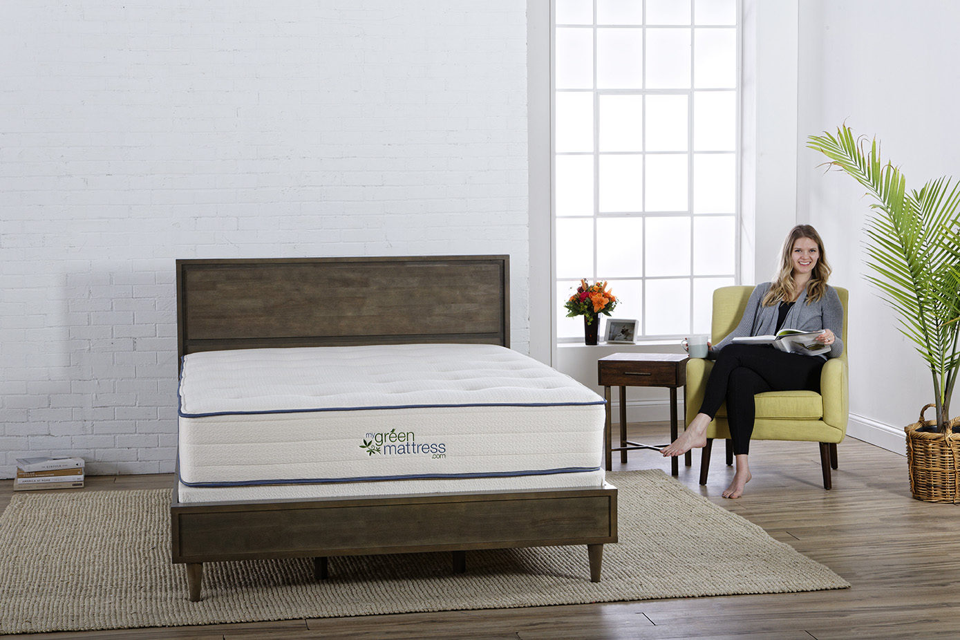 woman sitting in a chair next to a bed with my green mattress organic mattress