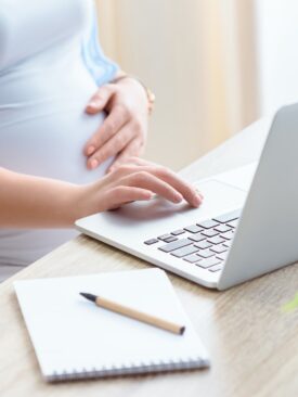 pregnant mom with left hand on belly while researching baby registry tips and hacks
