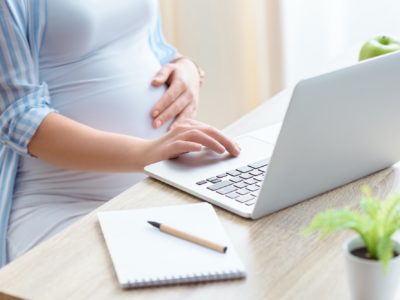 pregnant mom with left hand on belly while researching baby registry tips and hacks