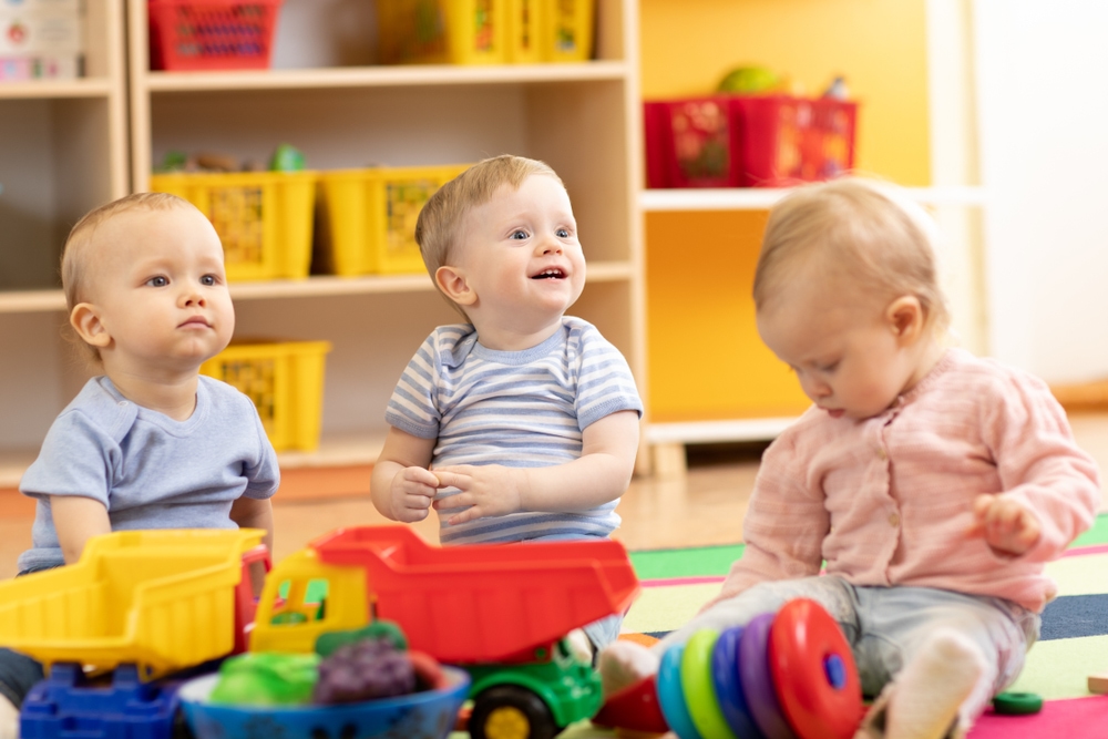 three toddlers playing with toys at daycare