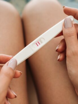 closeup of woman holding positive pregnancy test
