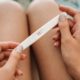 closeup of woman holding positive pregnancy test