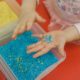 closeup of toddler playing in sensory play bins with rice dyed different colors