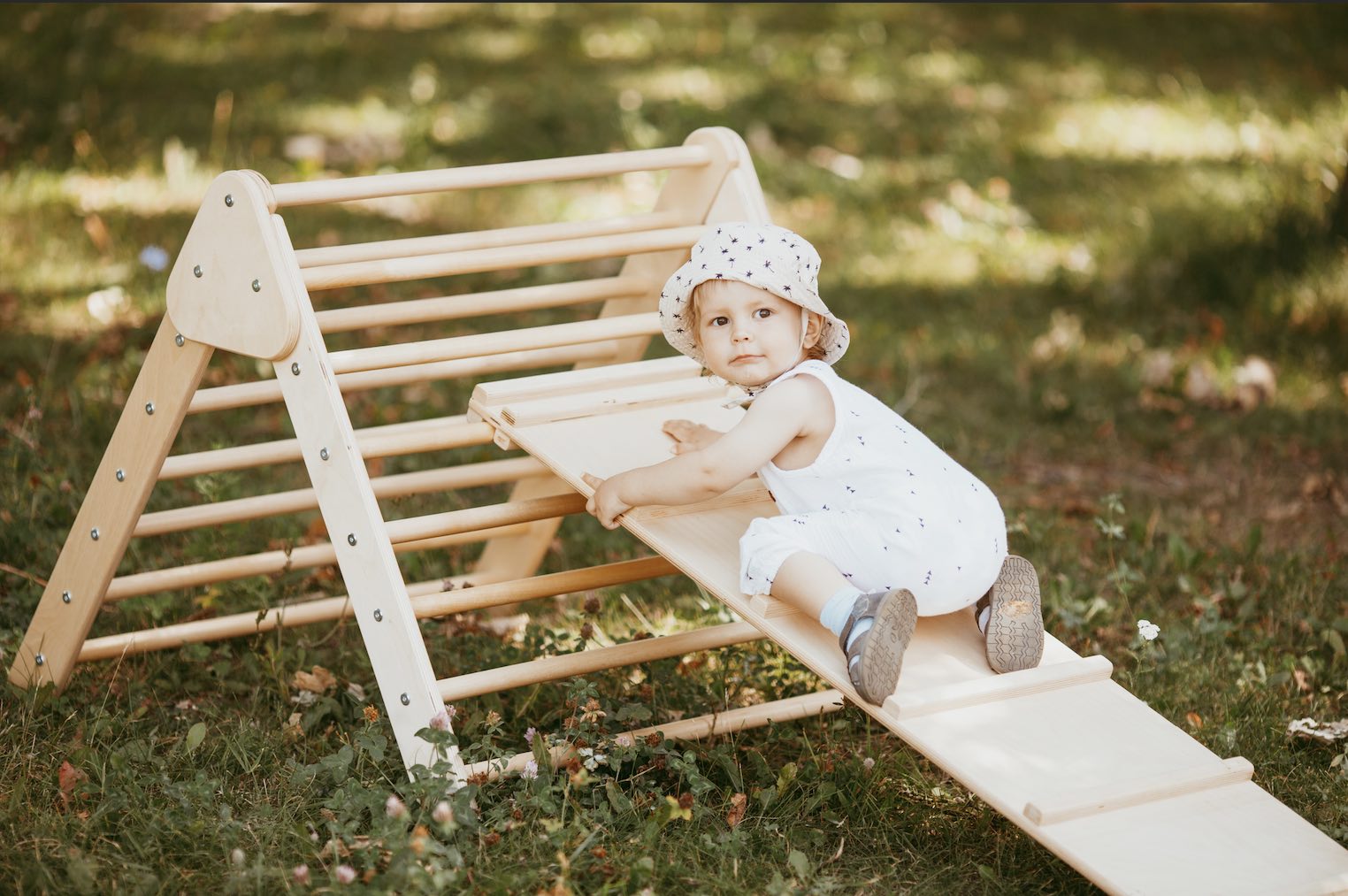cute baby outdoors climbing on pikler triangle climbing set