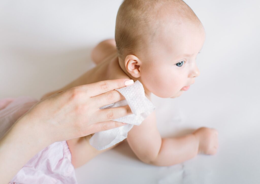 closeup of baby with parent wiping non-toxic baby wipe on baby's back